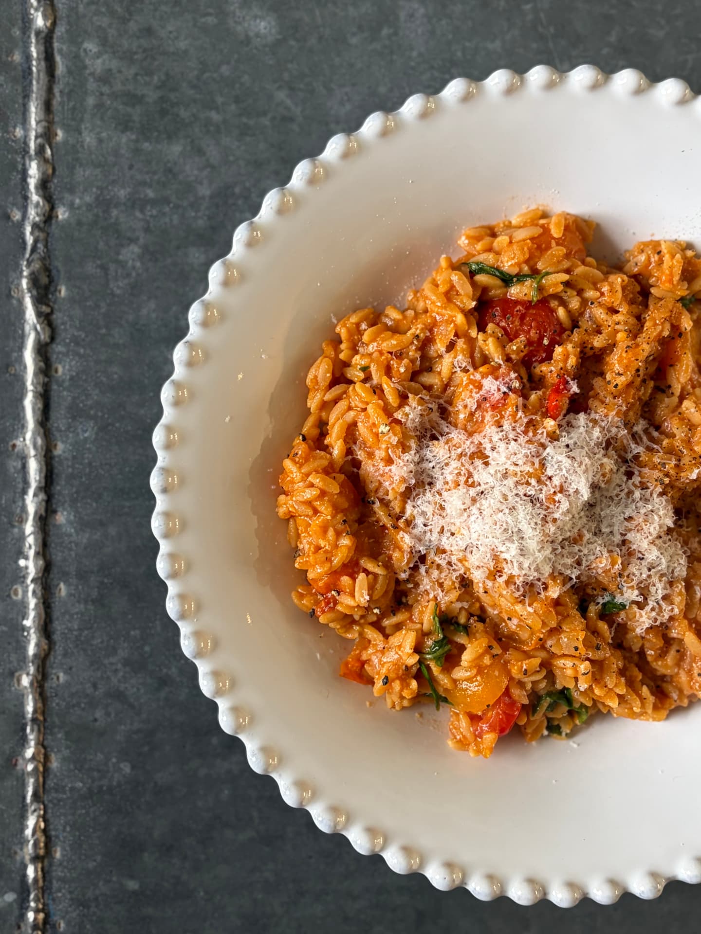 A plate of tomato orzo topped with grated parmesan, a simple balanced everyday meal