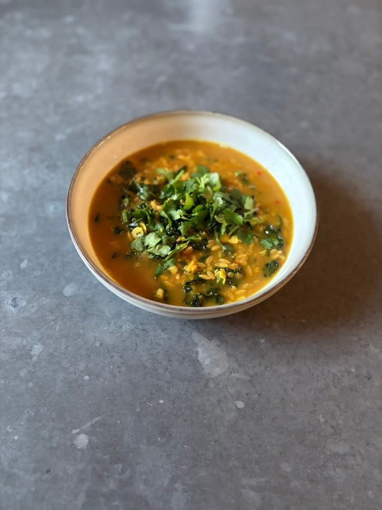 High protein coconut ginger soup with red lentils and greens in a bowl